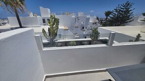 A white building with a flat roof, satellite dishes, and cacti.