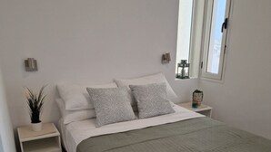 Ein ordentlich eingerichtetes Schlafzimmer mit einem Bett, Nachttischen, einem Fenster und einer kleinen Ablagefläche mit Dekoration.