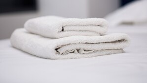 A neatly folded white towel on a bed in a hotel room. - Athens luxury suite 26 m2  (Athina)