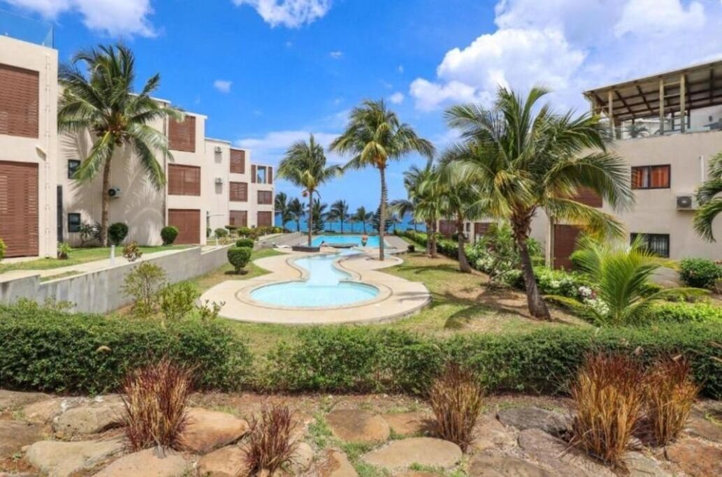 Um resort com piscina, palmeiras e edifícios modernos.