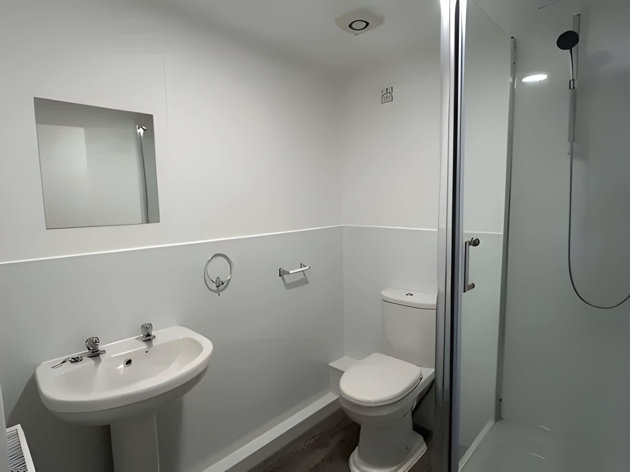 Un baño moderno con lavamanos, inodoro y ducha.