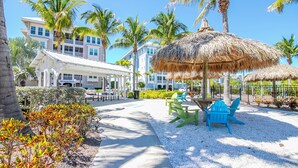 A resort with outdoor seating, palm trees, and a building with multiple balconies.