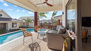 A covered outdoor area with a pool, seating, and a ceiling fan.