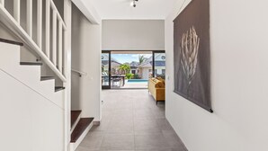 A modern interior with a staircase, a large artwork on the wall, and a view of an outdoor patio area.