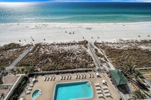 An aerial view of a beach resort with a swimming pool, beach chairs, and a lifeguard tower. - Ocean Ritz 902 Beachfront, Heated Pool, Hot Tub, Gym, FREE Daily Golf&Perks! (Panama City Beach)