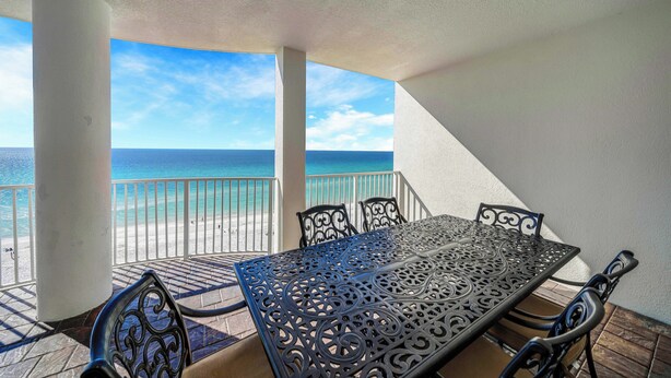 Ein Balkon mit Tisch und Stühlen mit Blick auf einen Strand.