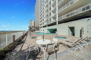 A hotel with a rooftop pool area, including lounge chairs and a table, and a view of the ocean. - Ocean Ritz 902 Beachfront, Heated Pool, Hot Tub, Gym, FREE Daily Golf&Perks! (Panama City Beach)