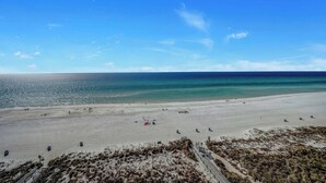 Ein weiter Sandstrand mit blauem Himmel und ruhiger See.