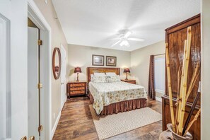 A bedroom with a bed, two bedside tables, a ceiling fan, and a window with curtains. - Ocean Ritz 902 Beachfront, Heated Pool, Hot Tub, Gym, FREE Daily Golf&Perks! (Panama City Beach)