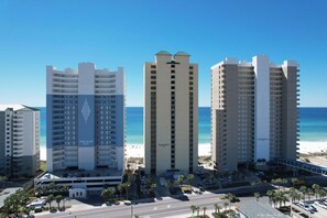 A beachfront hotel complex with multiple high-rise buildings, a parking area, and a clear view of the ocean.