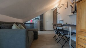 A compact living space with a sofa, a dining table with chairs, a kitchenette, and a wooden cabinet. - Filiberto Studio by Wonderful Italy (Turin)