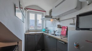 A compact kitchen with dark cabinets, a sink, a kettle, and a refrigerator. - Filiberto Studio by Wonderful Italy (Turin)