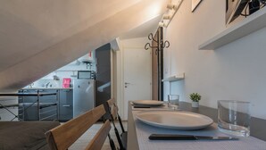 A compact kitchen with a microwave, refrigerator, and a small dining area with a bench and table. - Filiberto Studio by Wonderful Italy (Turin)