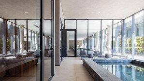 A modern indoor pool area with glass walls, lounge chairs, and a clear view of the outside. - PERFECT STUDIO ITAIM / FARIA LIMA PARKING SPACE  (Vila Olímpia São Paulo)