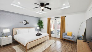 A modern bedroom with a bed, bedside tables, a ceiling fan, and a view through a glass door. - Best of Desoto 4BR,3BA with Pool, HotTub, Cinema (DeSoto)