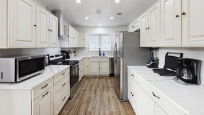 A modern kitchen with white cabinetry, stainless steel appliances, and a tiled floor. - Best of Desoto 4BR,3BA with Pool, HotTub, Cinema (DeSoto)