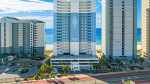 Un hôtel doté d’une tour centrale, d’un parking et offrant une vue sur la plage.