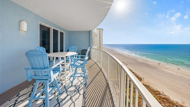 Un balcon avec une table et des chaises, donnant sur une plage.