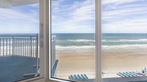 A balcony with a view of the beach and ocean.
