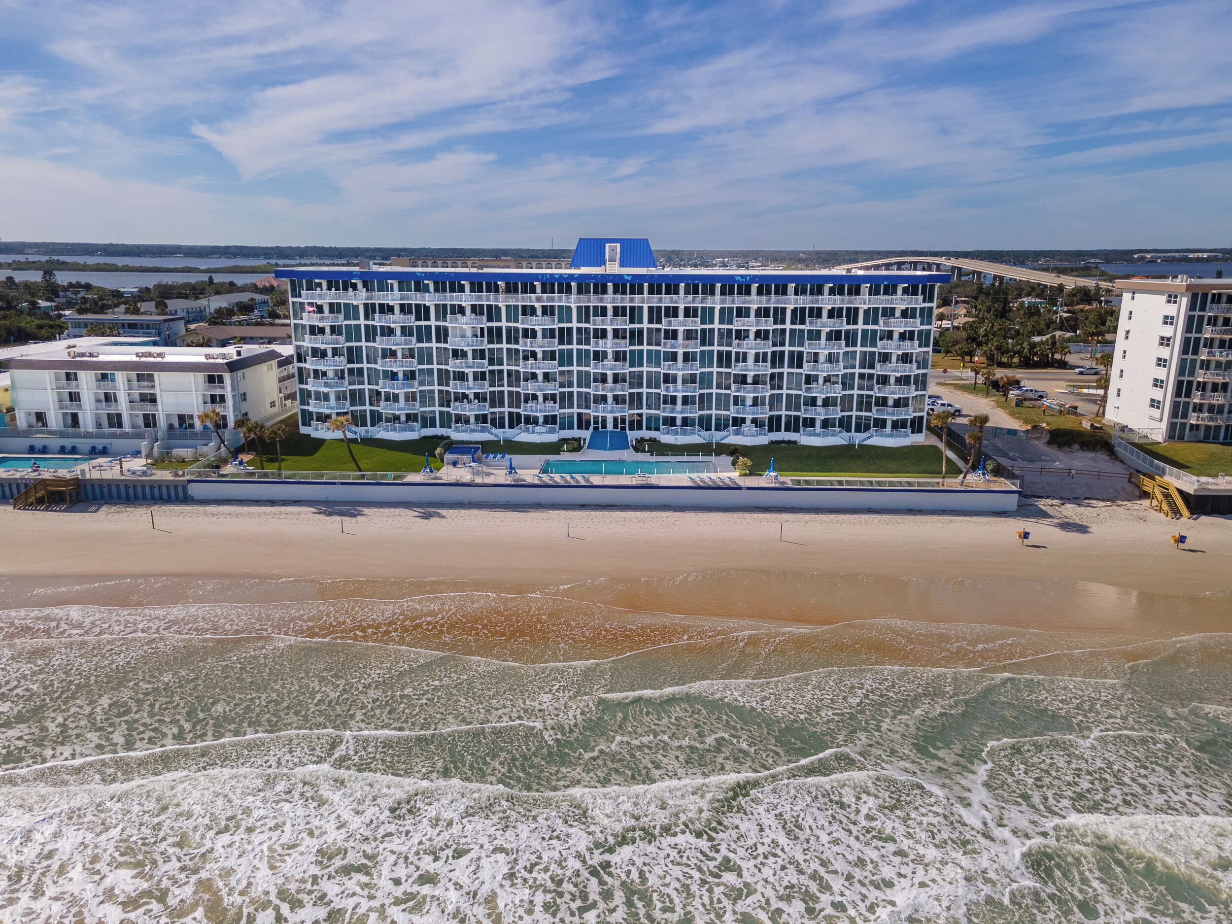 Ein Strandhotel mit Pool, Liegestühlen und Sonnenschirmen.