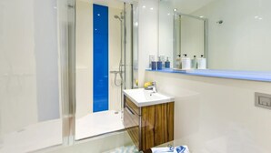 A modern bathroom with a glass shower enclosure, a white sink, and a mirror above it. - Chapel Heights in Durham (Durham)