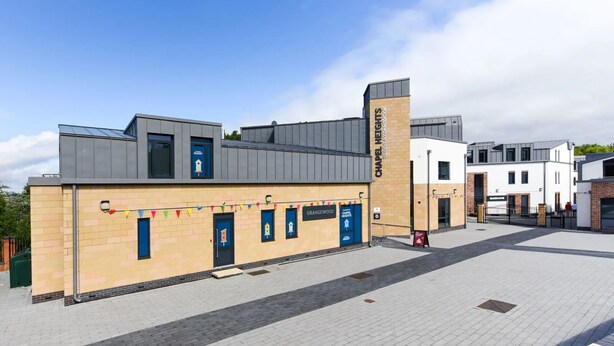 A modern building with a flat roof, a prominent vertical sign, and a series of blue doors with white signage. - Chapel Heights in Durham (Durham)
