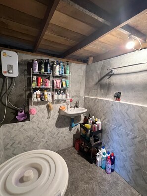 Une salle de bain avec des toilettes blanches, un lavabo et des étagères remplies de produits de toilette.