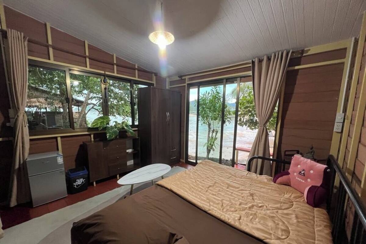 Quarto com cama, escrivaninha e vista para o mar.