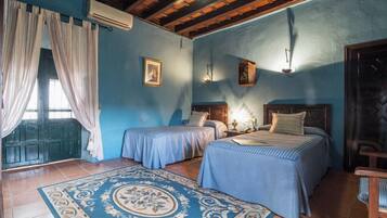 A room with two beds, a patterned rug, and a window with curtains.