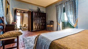 Um quarto com cama, um armário de madeira, uma cadeira e uma janela com cortinas.