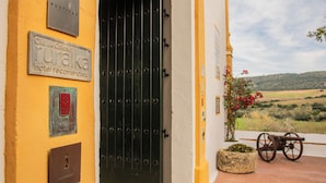 Um edifício com porta preta, paredes amarelas e uma placa indicando 'Ruralaka Hotel Recomendado'.