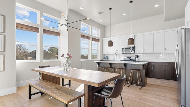 A modern kitchen with a wooden dining table, bar stools, and a large island. - Villa #02 at Bloomington Country Club: Pool, Golf, Restaurant (St. George)