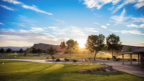 A golf course with a well-maintained lawn, a putting green, and a pavilion.