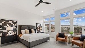 A modern bedroom with a large bed, a nightstand, a chair, and a small table. - Villa #36 at Bloomington Country Club: Pool, Golf, Restaurant (St. George)