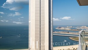 Un immeuble de grande hauteur doté d’une architecture moderne, offrant une vue sur une zone côtière avec un port de plaisance et un pont.