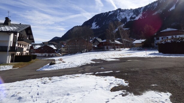 Un village de montagne enneigé, avec des bâtiments et une route.