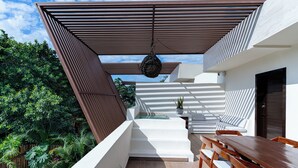A modern outdoor patio with a wooden table and chairs, a white sofa, and a hanging light fixture. - Villa in Tulum with Private Pool and Jacuzzi (Tulum)