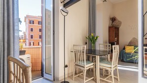 Un salon moderne doté d’une porte vitrée donnant sur un balcon, d’une table à manger avec des chaises et d’un canapé agrémenté d’un coussin décoratif.