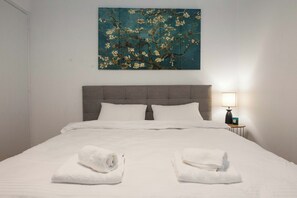 A neatly made bed with white linens and two towels folded at the foot of the bed. - Stylish Renovated 2 Bd Apt in Exarcheia (Athens)