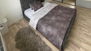 A modern bedroom with a tufted headboard, a large mirror, and a fluffy rug. - Bright and modern apartment in Cesis, Luxurious  stay at modern apartment (Cesis) (Cēsis)