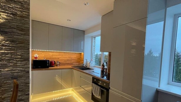 A modern kitchen with sleek cabinetry, a wooden countertop, and under-cabinet lighting. - Bright and modern apartment in Cesis, Luxurious  stay at modern apartment (Cesis) (Cēsis)