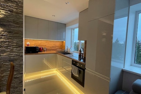 A modern kitchen with sleek cabinetry, a wooden countertop, and under-cabinet lighting.