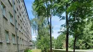A courtyard with a pathway, a small garden with orange flowers, and a building with multiple windows. - Bright and modern apartment in Cesis, Luxurious  stay at modern apartment (Cesis) (Cēsis)