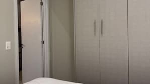 Un dormitorio con cama, armario y aire acondicionado.