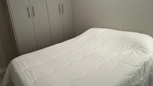 Un dormitorio con una cama, un armario y una pared lisa.