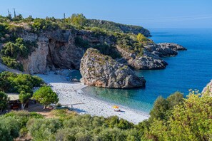 A coastal beach with rocky formations and clear blue waters.
