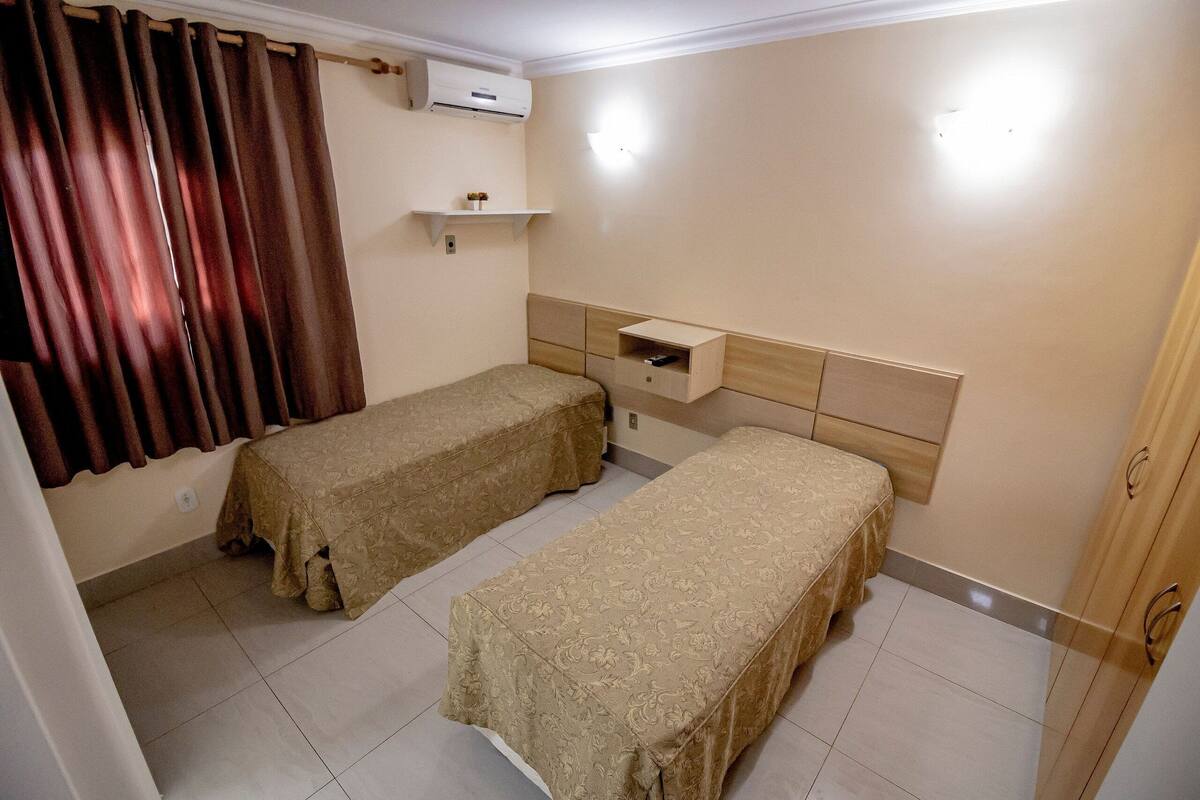 Ein Zimmer mit zwei Betten, einem Regal mit einem kleinen Gegenstand und einer Klimaanlage.