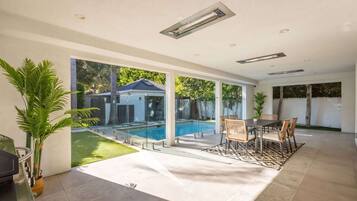 Un intérieur moderne avec une piscine, des portes vitrées et un coin repas.