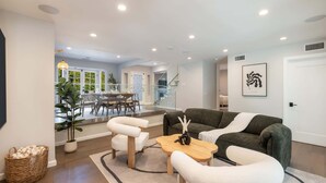 Un salon moderne comprenant un canapé, des fauteuils, une table basse et un coin repas avec une table et des chaises.
