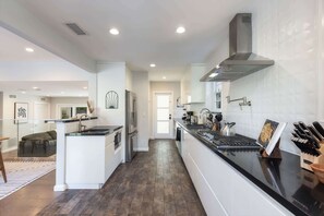 A modern kitchen with a central island, stainless steel appliances, and a view into the living area.